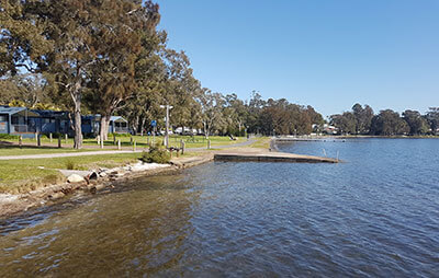 Seawall at Mannering Park foreshore with cabins in background