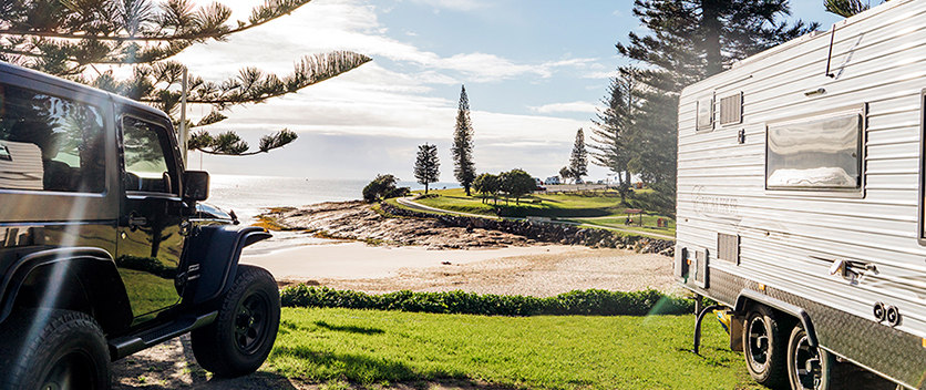 Car and caravan parked at Horseshoe Bay Holiday Park. Credit: Destination NSW