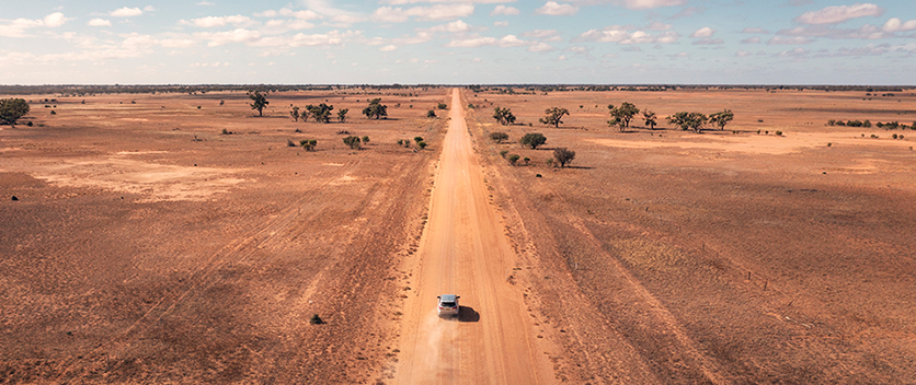 Aerial overlooking a vehicle driving along outback road. Credit: Destination NSW