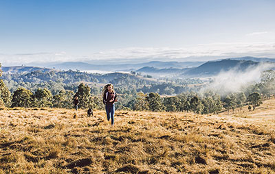 Girl running with her dog on a track on a hill