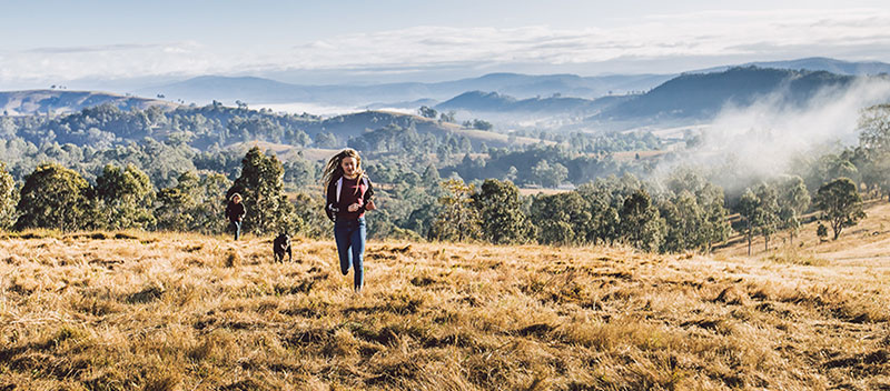Girl running with her dog on a track on a hill