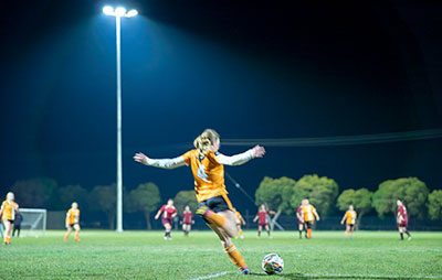 Girl playing soccer under lights in sportsground