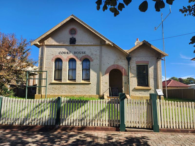 Front of restored historic Court House with picket fence and gate