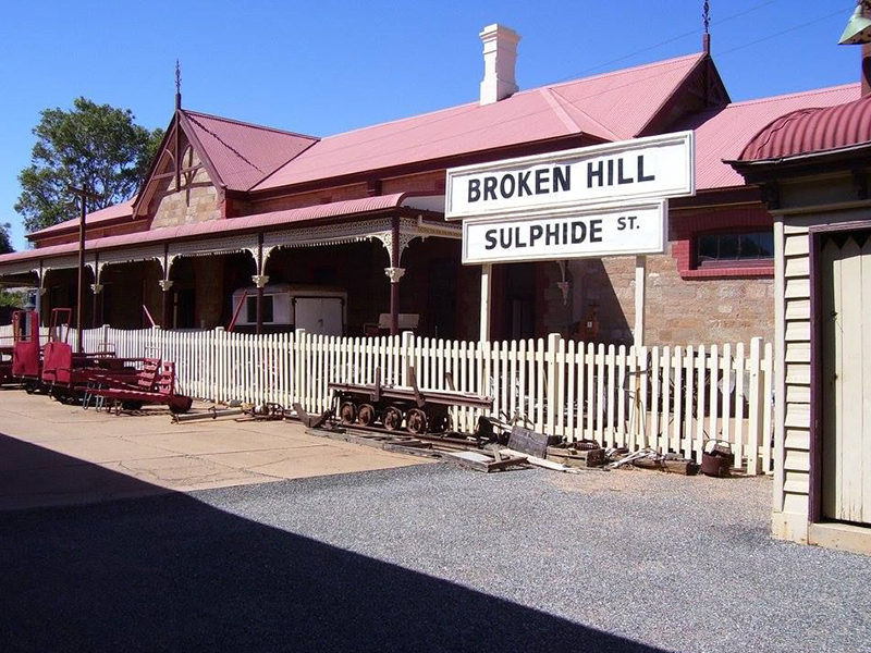 A federation building in Broken Hill. A hand-painted sign sits above a picket fence and reads Broken Hill Sulphide St in thick, black writing.