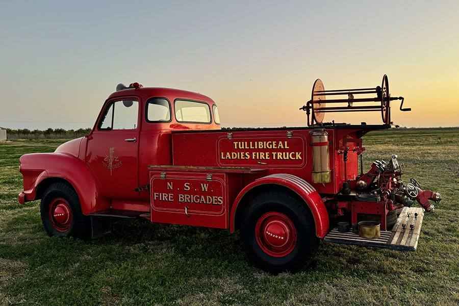 An old fire truck after being restored parked in a field being used as a tourist attraction in a rural community..