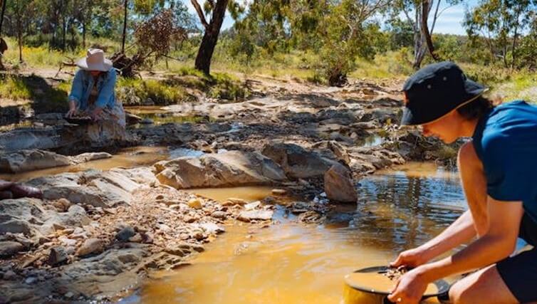 Man and woman fossicking in a creek