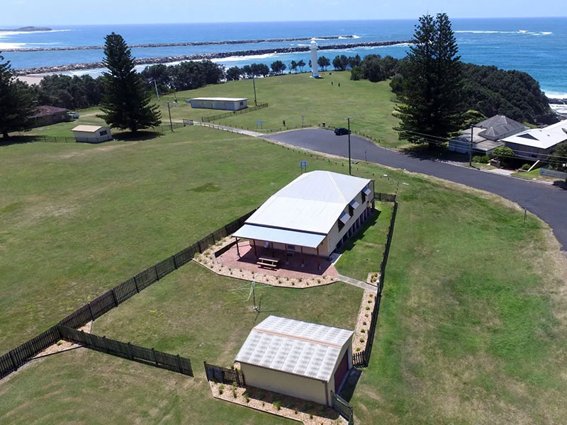 Aerial view of cottage buildings in field with ocean in distance