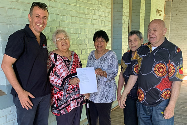 L to R - Crown Lands officer Shane Smith hands over the Certificate of Title to Coonabarabran Local Aboriginal Land Council Board members Irene Nixon, Margaret Leslie, Beryl Dowd and Casey Dowd. People standing outside Coonabaraban Police station